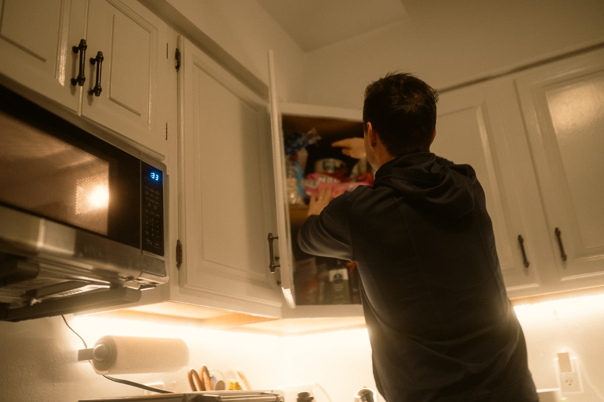 Rider reaching into kitchen cabinet in early morning light