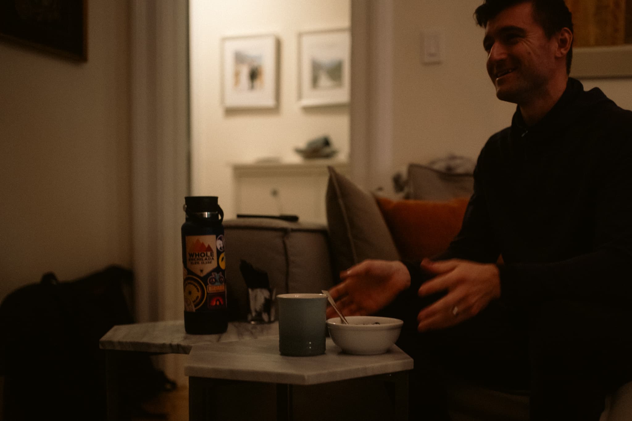 Rider eating breakfast on the couch, water bottle and mug on side table