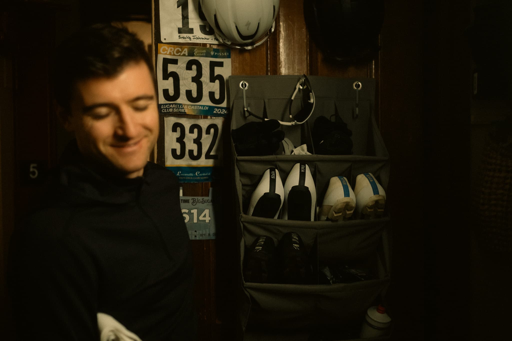 Rider smiling next to race bib numbers and shoe organizer