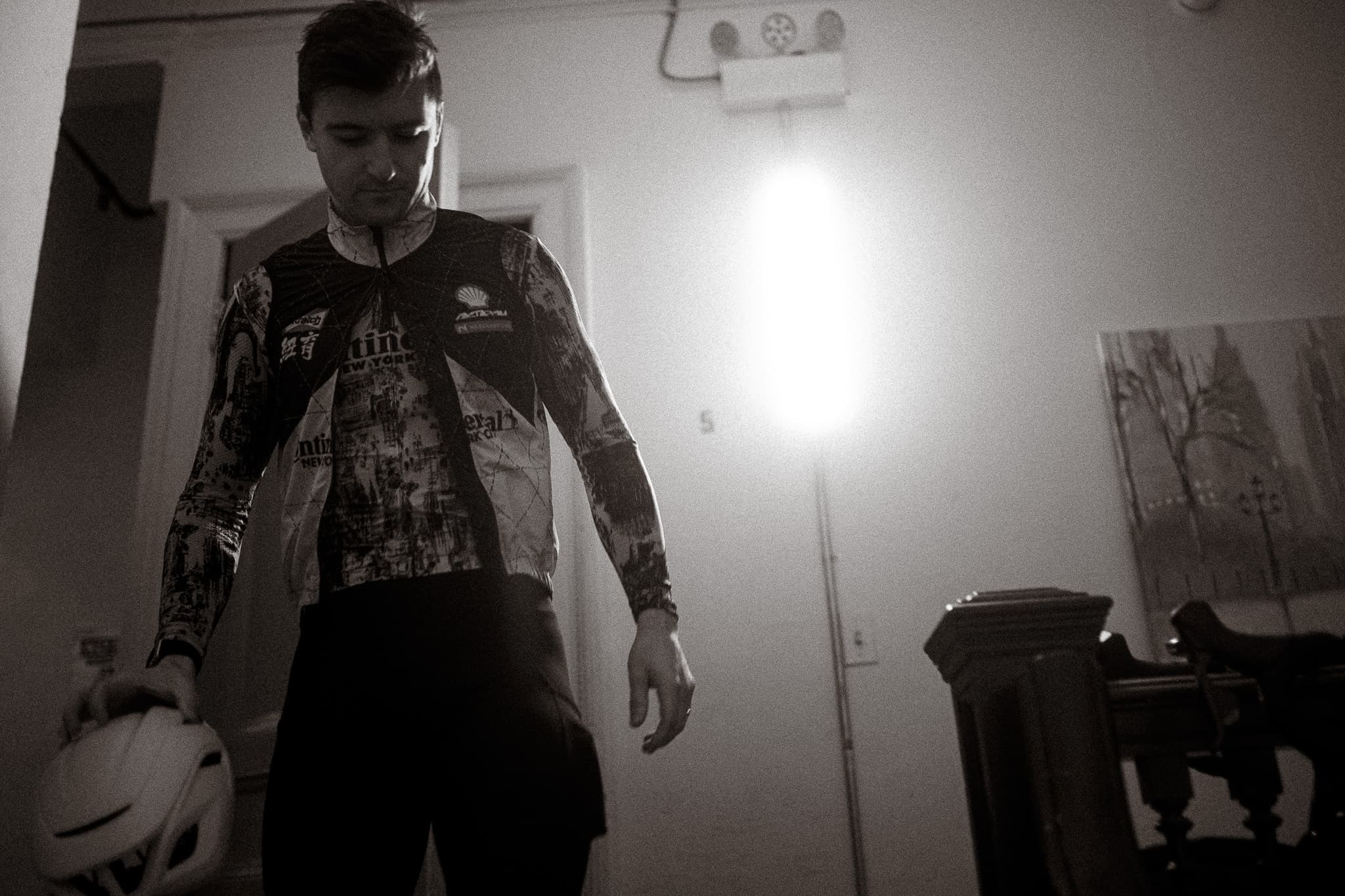 Rider in full kit holding helmet, looking down