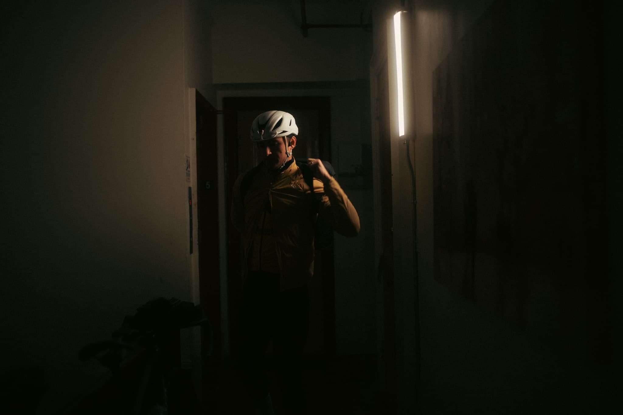 Rider adjusting strap in dark corridor lit by a single strip light