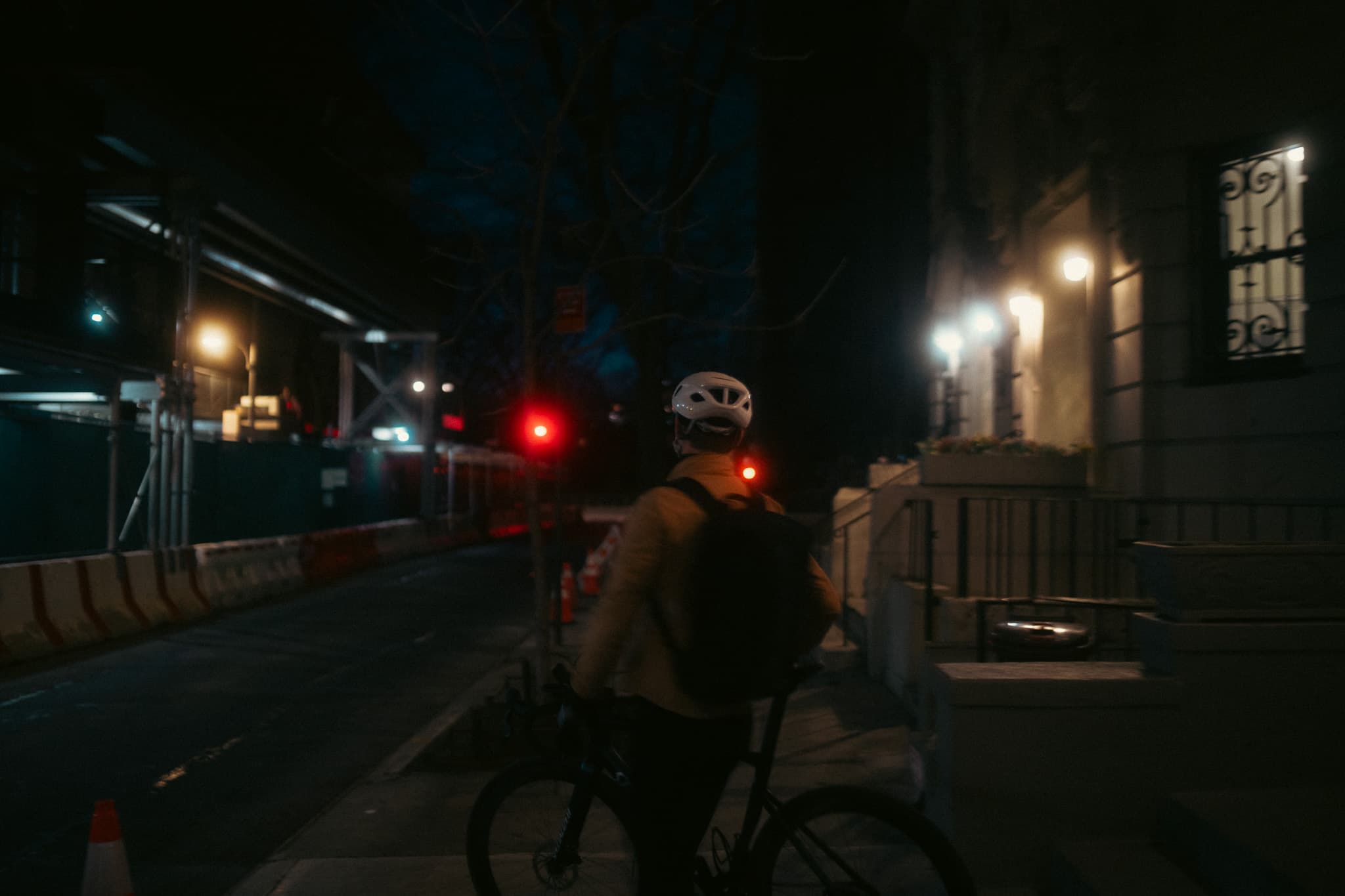 Rider cycling away on a night street, red tail light glowing