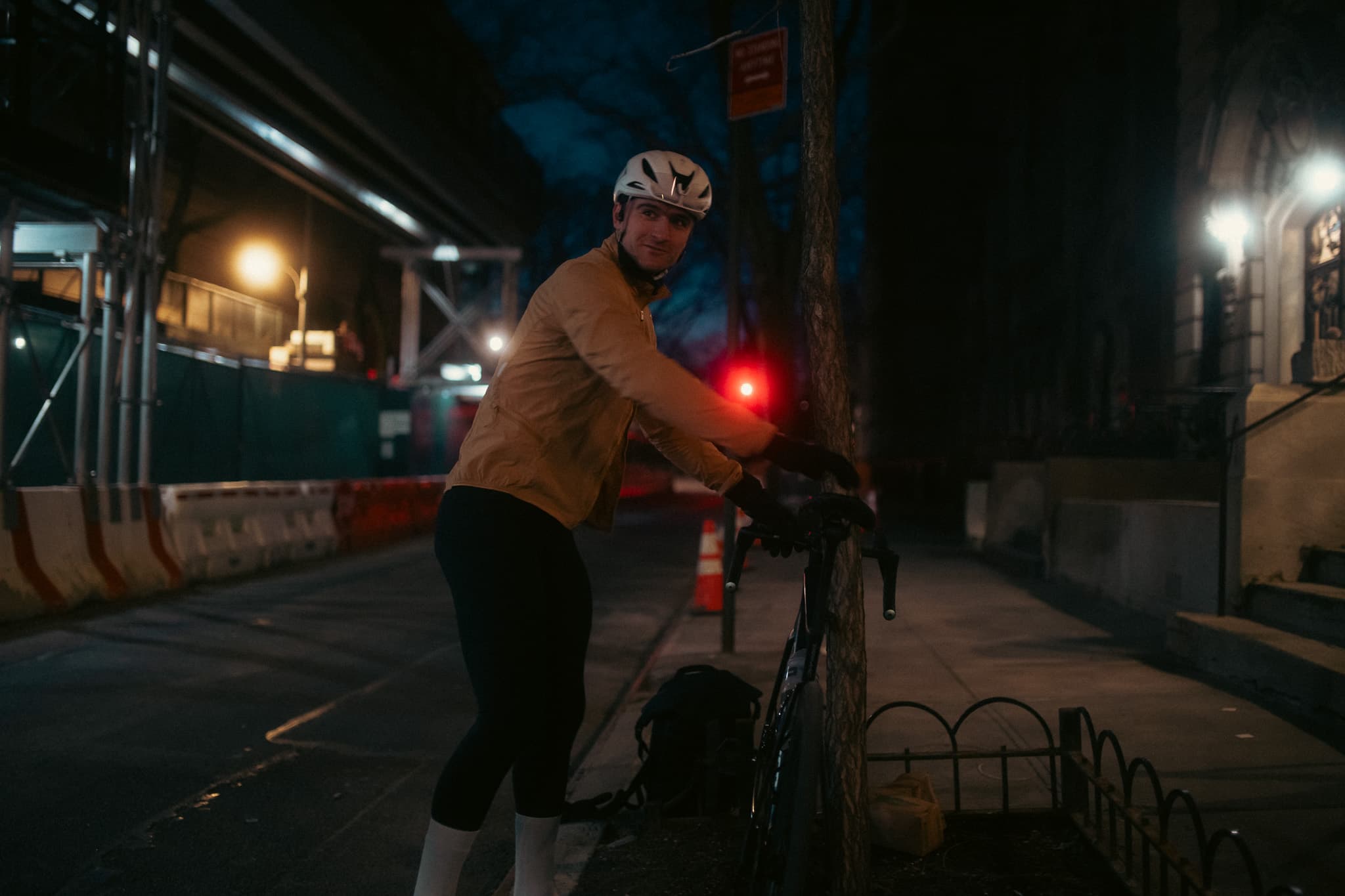 Rider looking back at camera on night street with bike