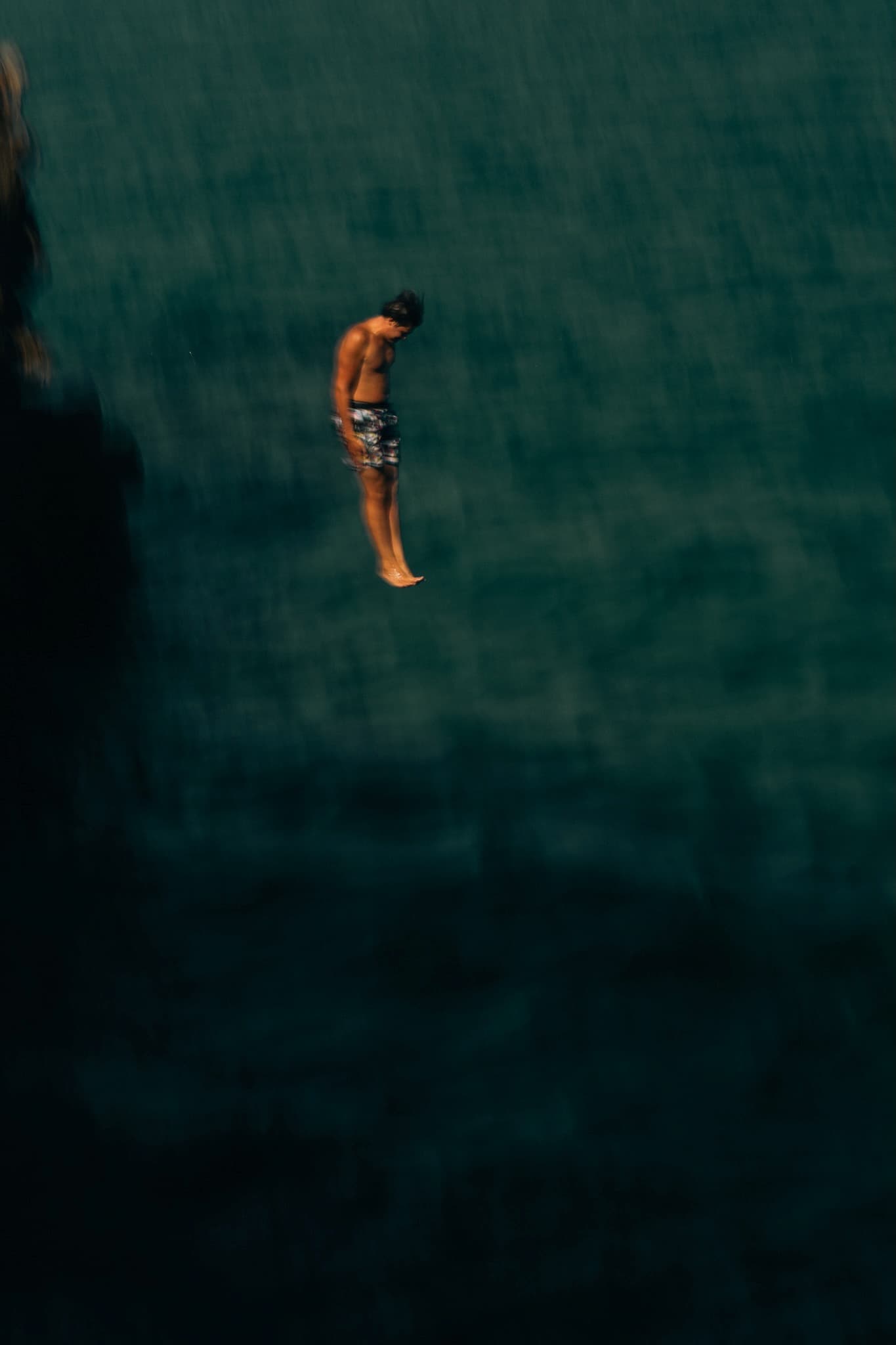 Figure suspended mid-fall against deep teal water