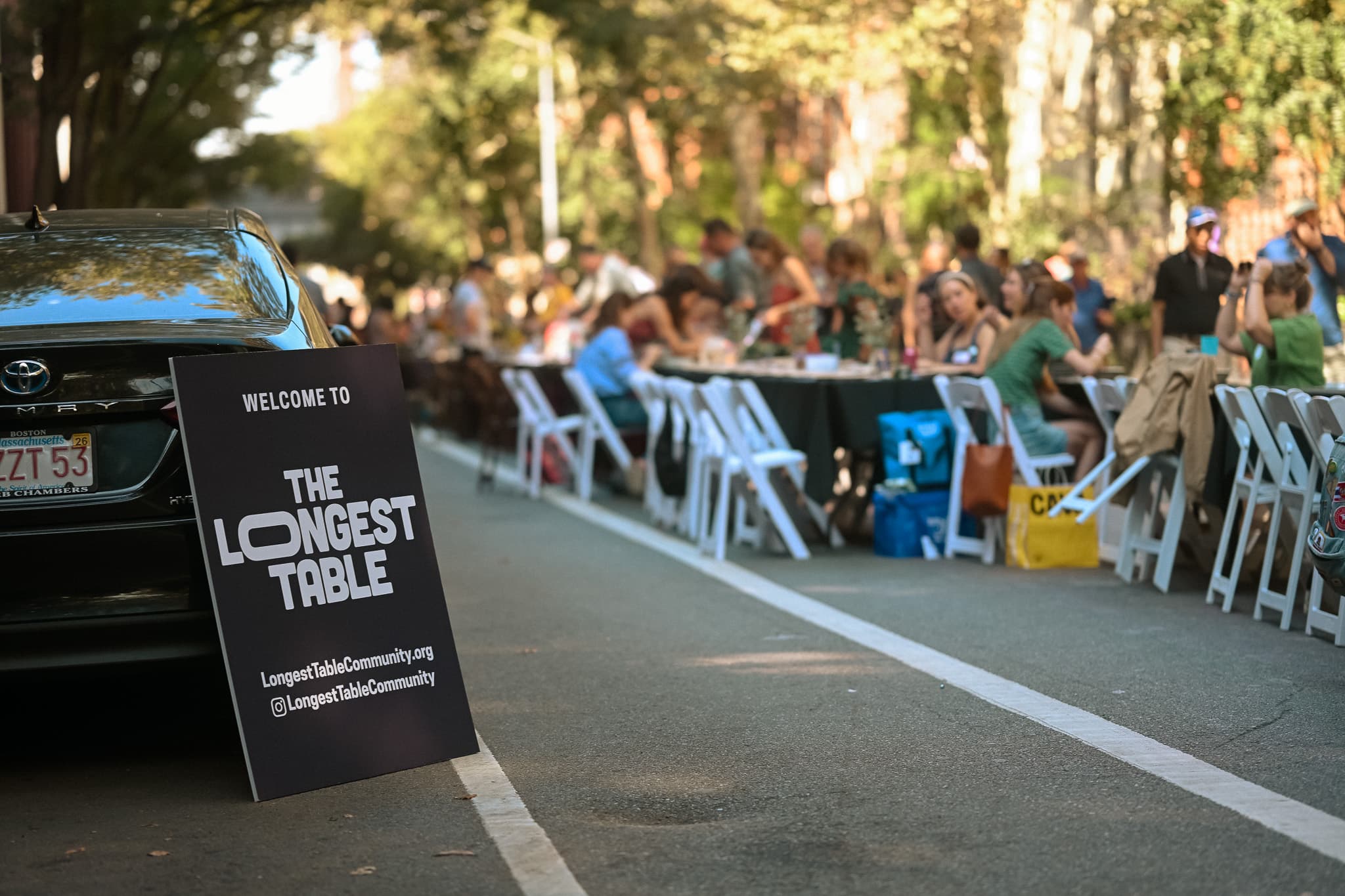 Welcome sign with long communal table stretching down the street